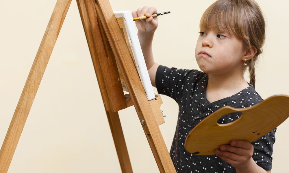 side-view-girl-with-down-syndrome-painting-with-easel